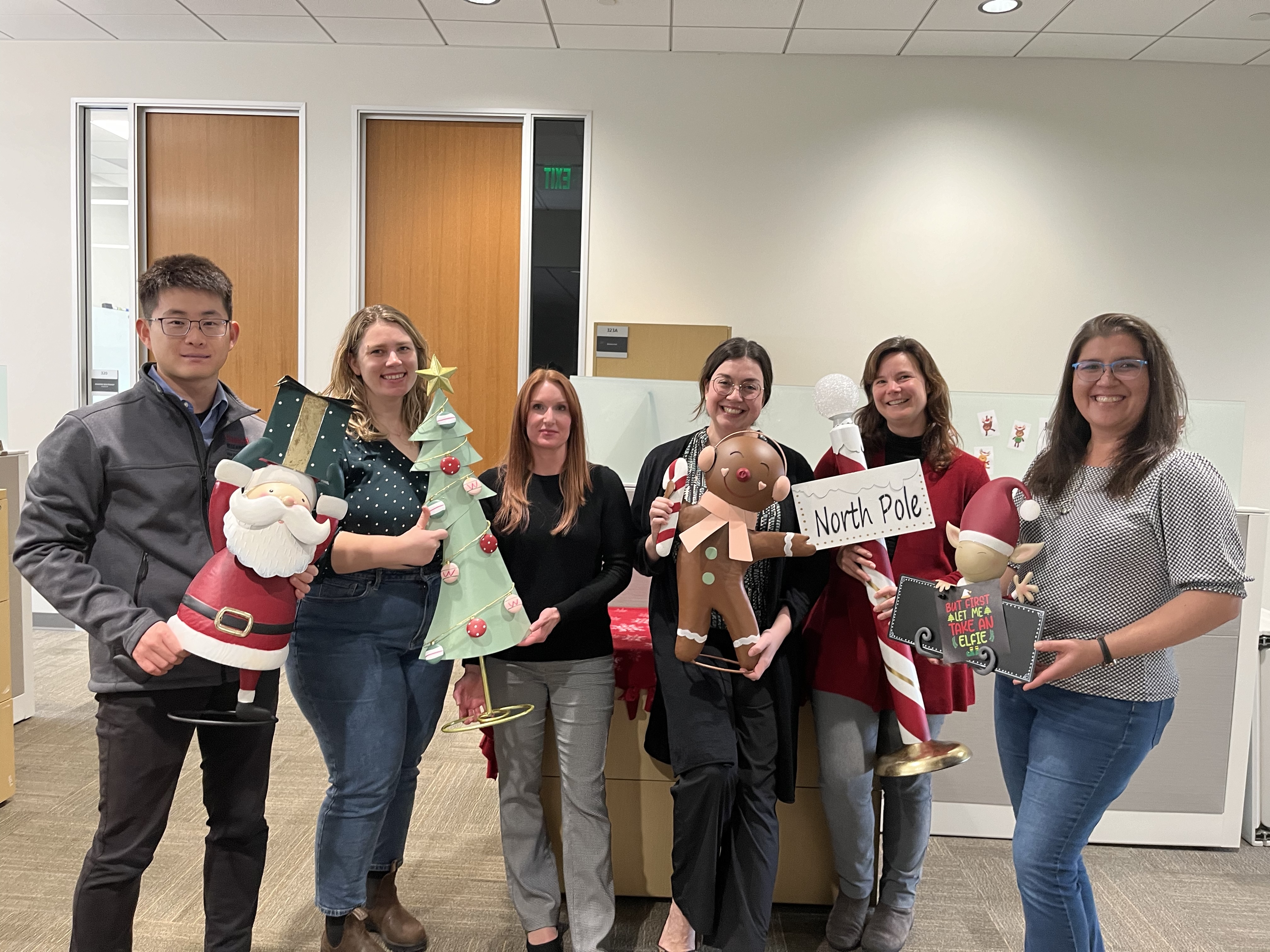 RDO team holding North Pole-themed holiday decorations and smiling