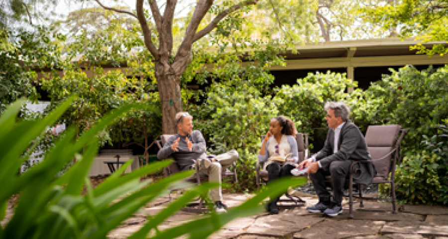 Three individuals talking in a CASBS courtyard