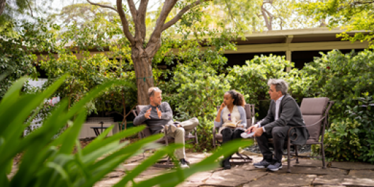 Three individuals talking in a CASBS courtyard